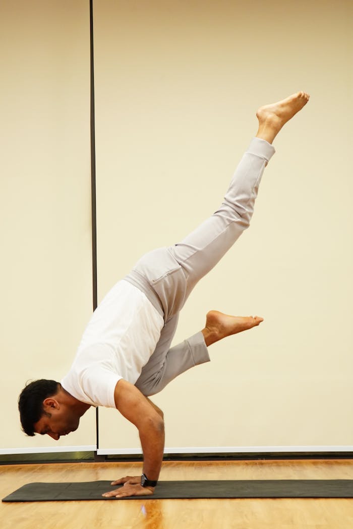 Crafting Captivating Headlines: Your awesome post title goes here Adult man practicing yoga handstand indoors, showcasing balance and strength.